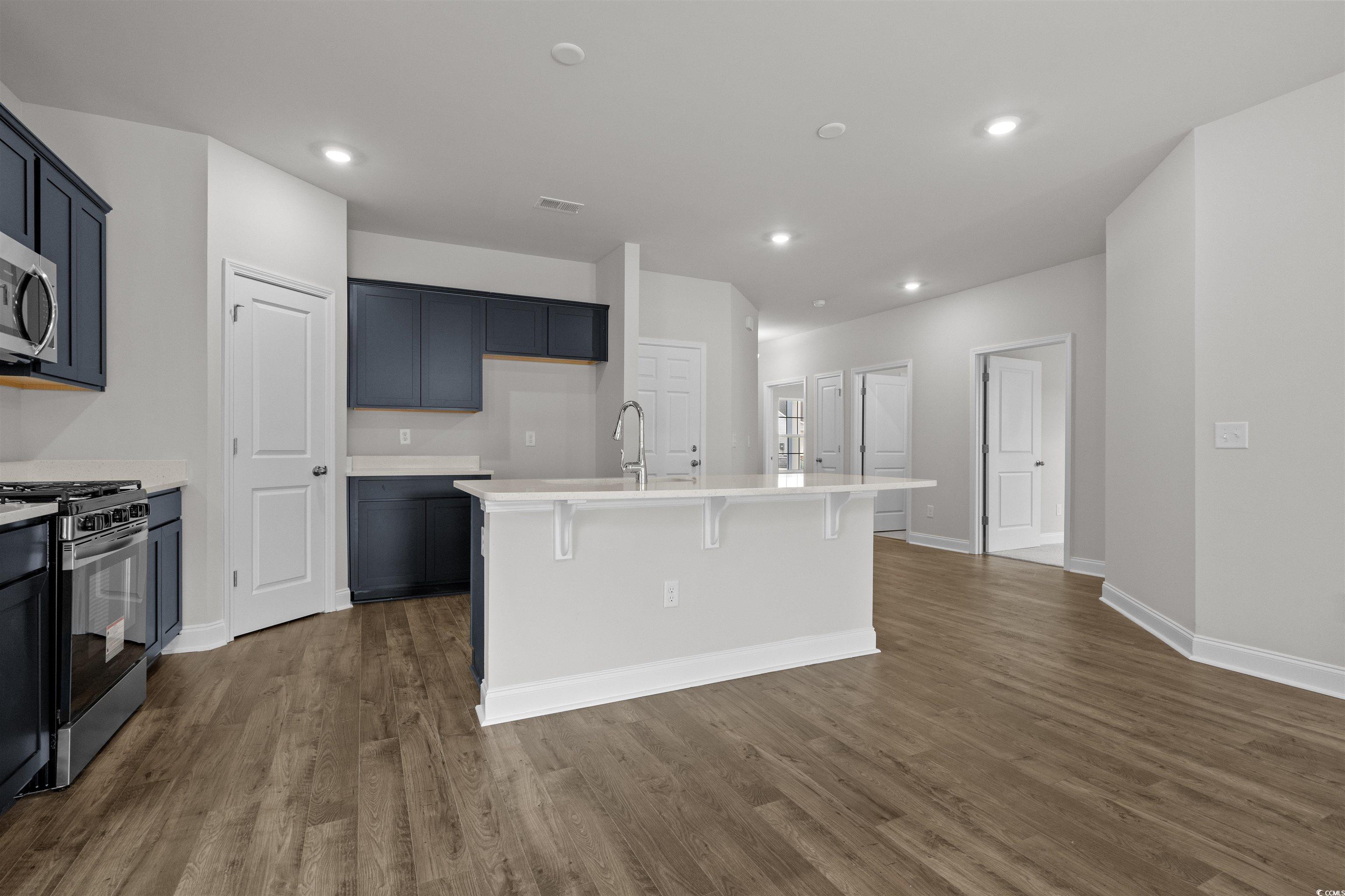 2494 Campton Loop Conway, SC 29527 - Photo 11 of 40 Kitchen with appliances with stainless steel finishes, a kitchen breakfast bar, dark wood-style flooring, a kitchen island with sink, and light stone counters