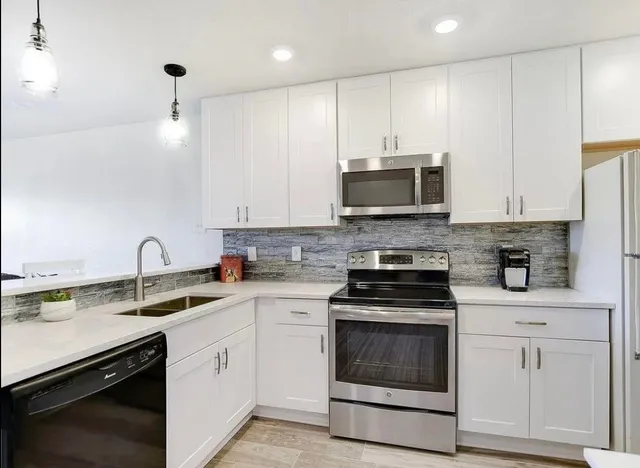 a kitchen with cabinets stainless steel appliances and a sink