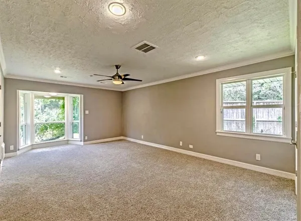 an empty room with windows and chandelier fan