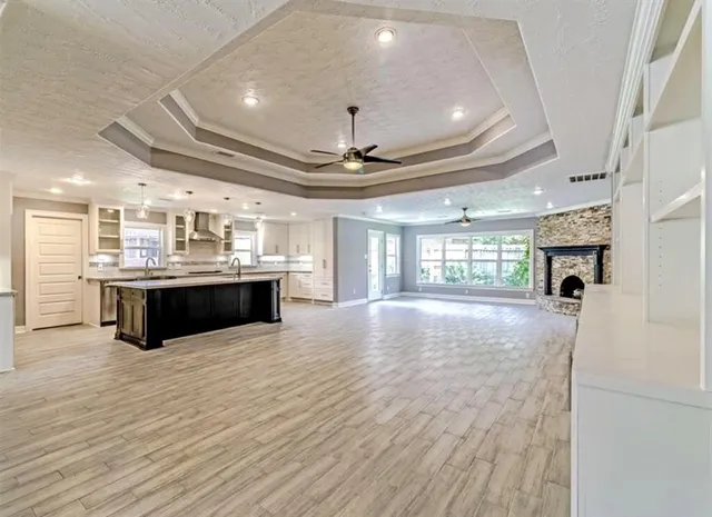 a large white kitchen with a large window a counter space a sink stainless steel appliances and cabinets