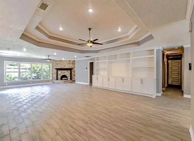 an empty room with wooden floor fireplace and windows