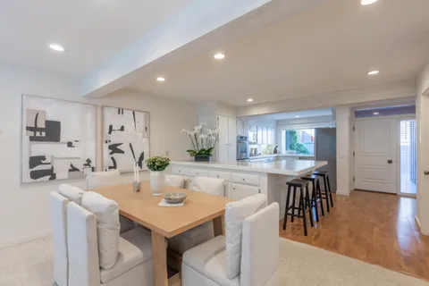 a kitchen with a dining table chairs and wooden floor