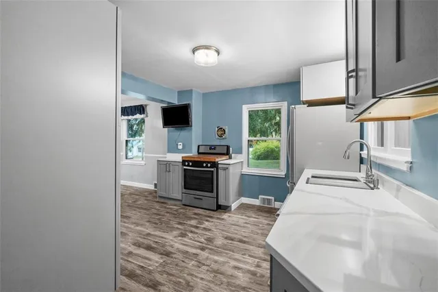 a kitchen with stainless steel appliances kitchen island granite countertop a sink stove and refrigerator