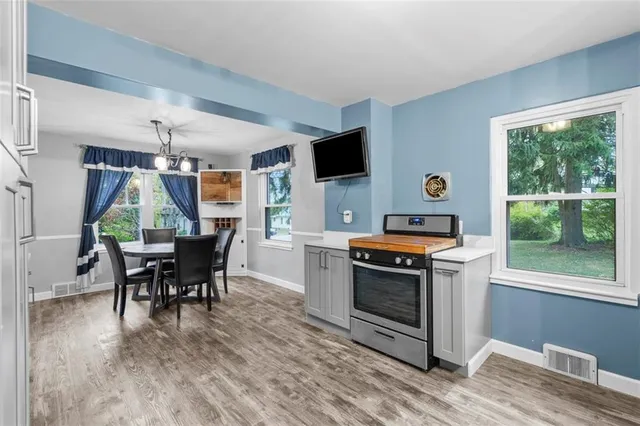 a kitchen with a stove a sink dishwasher a stove and a dining table with wooden floor