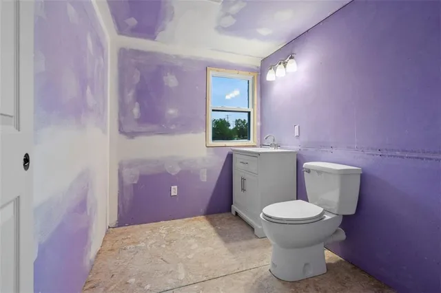 a bathroom with a granite countertop toilet a sink and a mirror