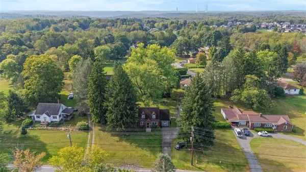 an aerial view of house with yard swimming pool and large trees