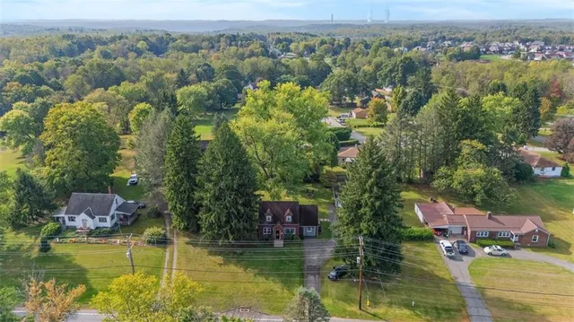 an aerial view of house with yard swimming pool and large trees
