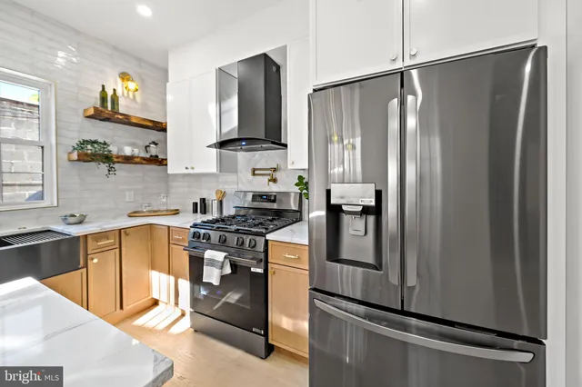 a kitchen with stainless steel appliances granite countertop a refrigerator a stove a sink dishwasher a oven a dining table and chairs with wooden floor