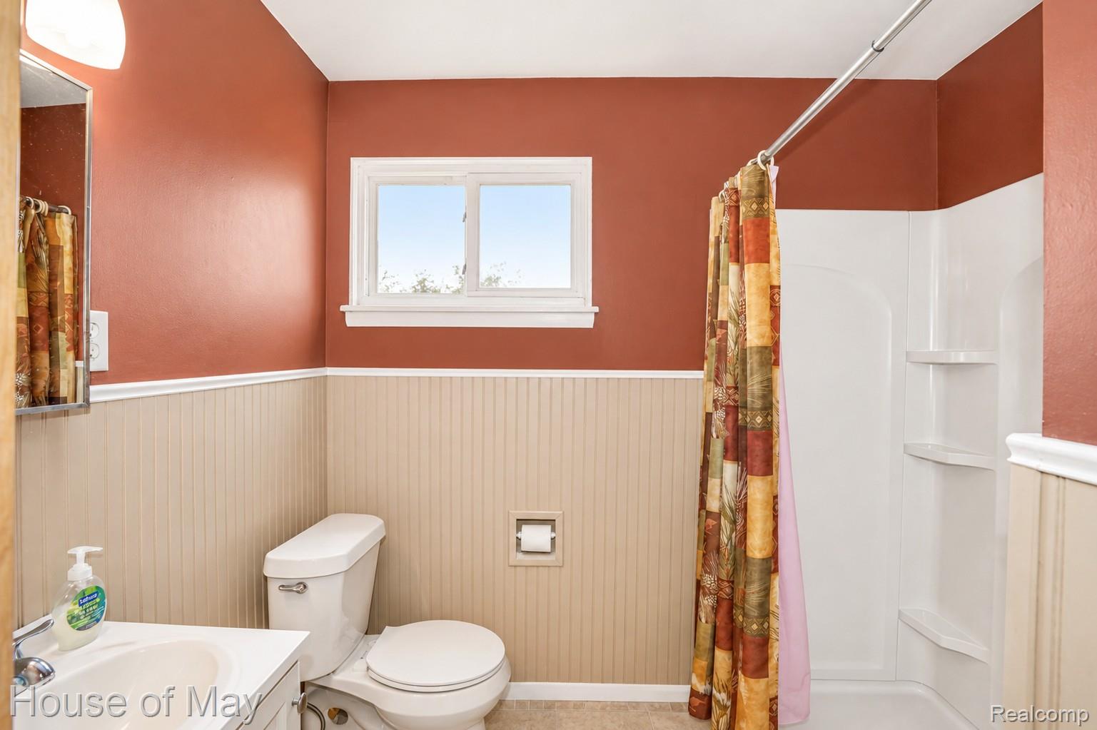 Bathroom featuring beadboard wainscoting, a white window frame, and a white shower-tub combination