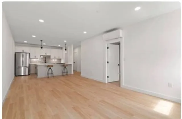 a view of kitchen with refrigerator and white cabinets