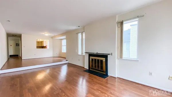 a view of an empty room with window and wooden floor
