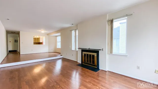 a view of an empty room with window and wooden floor