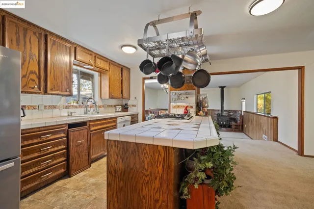 a kitchen with stainless steel appliances kitchen island granite countertop a sink dishwasher and a fireplace with wooden floor