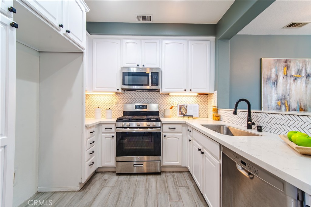 21 Thorp Ladera Ranch, CA 92694 - Photo 17 of 43 a kitchen with stainless steel appliances a stove a sink cabinets and a wooden floor