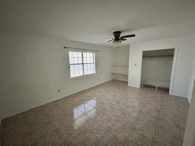 an empty room with windows and ceiling fan