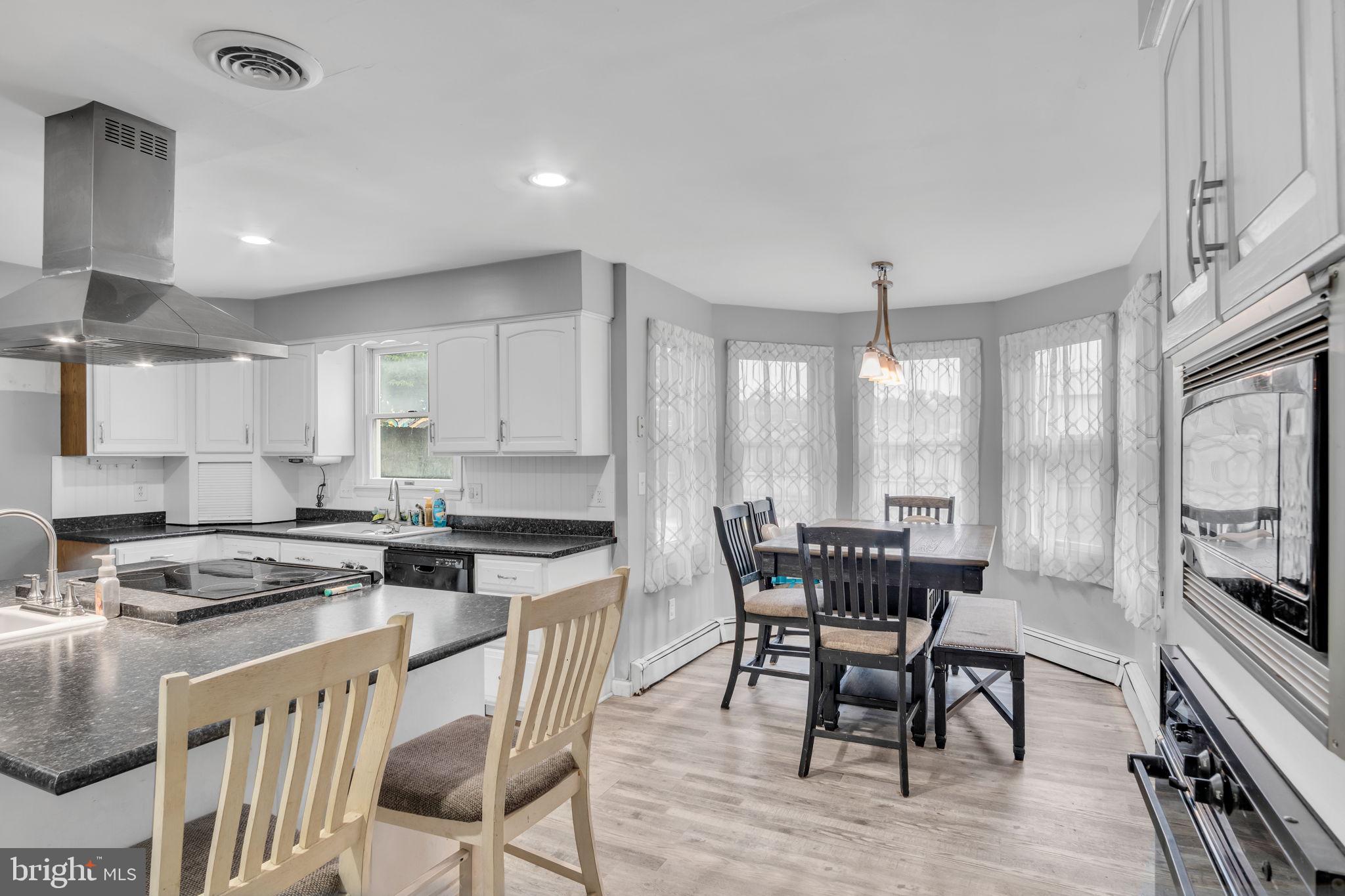 16 Hill Road Carlisle, PA 17015 - Photo 12 of 36 a kitchen with stainless steel appliances granite countertop a stove a sink a microwave a dining table and chairs with wooden floor