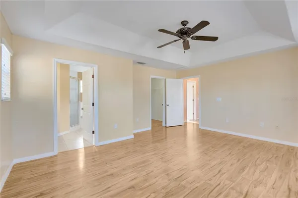 an empty room with wooden floor ceiling fan and windows