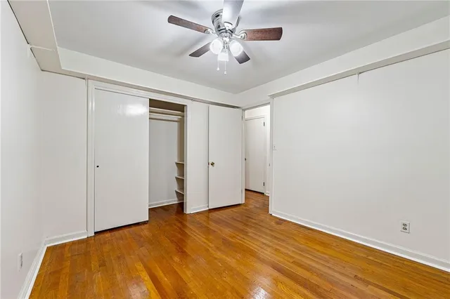 a view of a big room with wooden floor and a chandelier fan