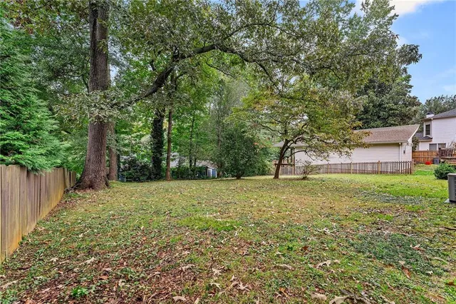 a view of a big yard with plants and large trees
