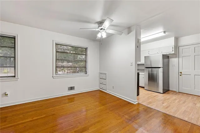 a view of empty room with wooden floor and kitchen view
