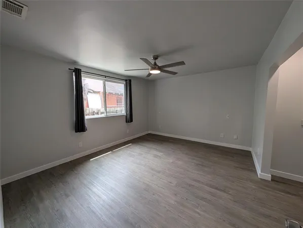an empty room with wooden floor ceiling fan and windows