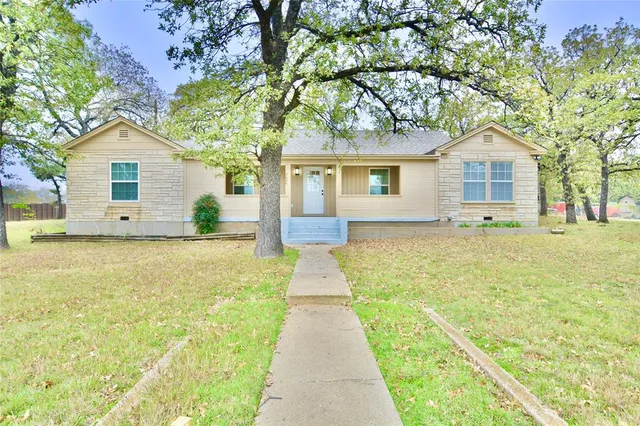 a front view of house with yard and trees around