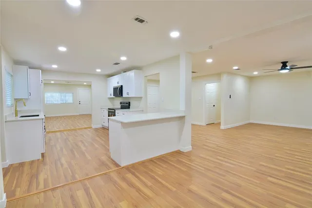a view of a big room with wooden floor and windows