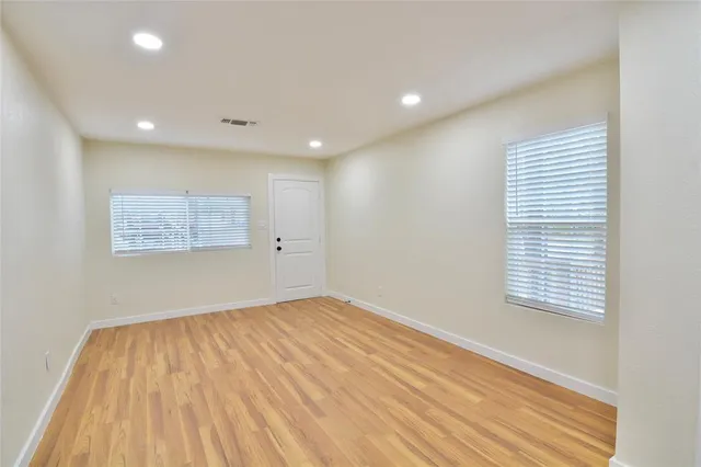 a view of empty room with wooden floor and fan