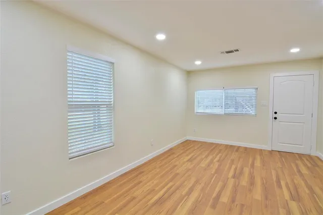 a view of an empty room with wooden floor and a window