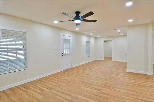 an empty room with wooden floor and windows
