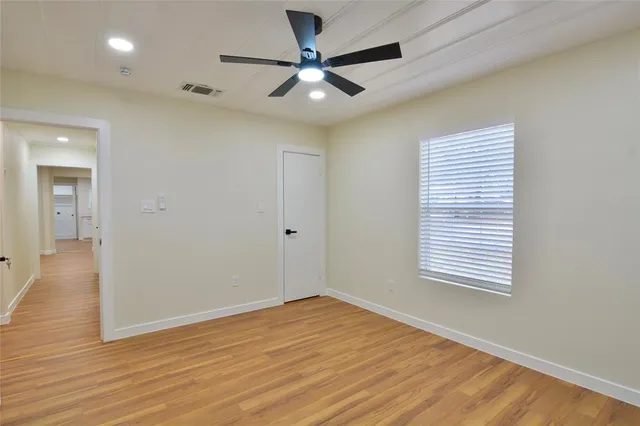 a view of an empty room with window and a ceiling fan