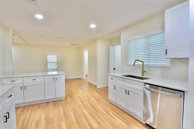a kitchen with a sink cabinets stainless steel appliances and wooden floor