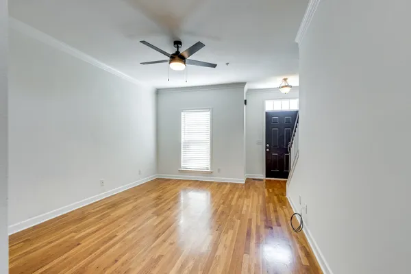 a view of an empty room with wooden floor and a window