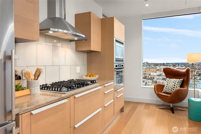 a kitchen with stainless steel appliances granite countertop a sink a stove and white cabinets next to a window