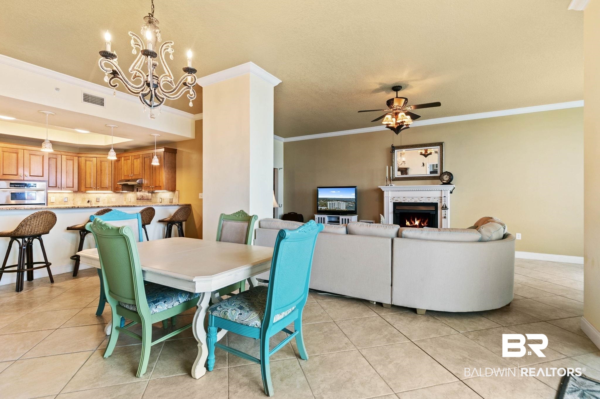 28250 Canal Road, Unit 208 Orange Beach, AL 36561 - Photo 8 of 53 Dining space with hanging lights, a lit fireplace, light tile patterned floors, a ceiling fan, and ornamental molding