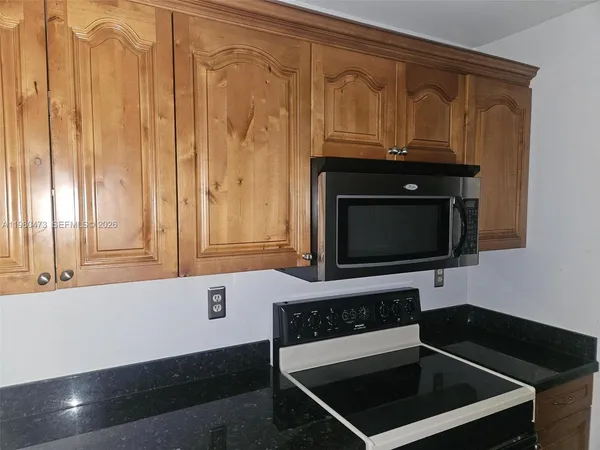 a kitchen with granite countertop a refrigerator and a sink