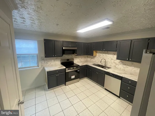 a large kitchen with granite countertop a sink and white cabinets