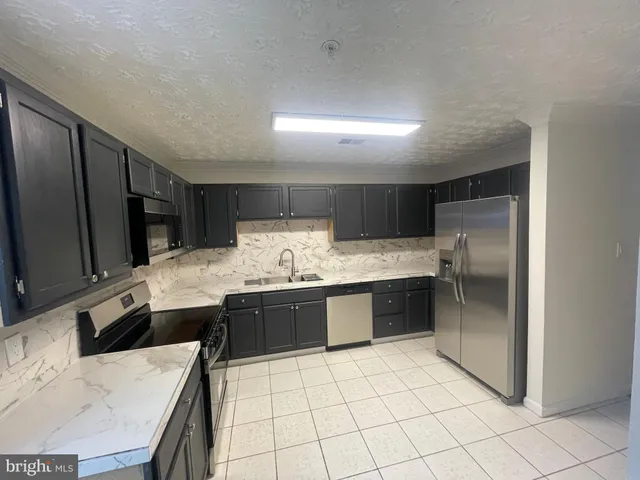 a kitchen with granite countertop a sink stainless steel appliances and cabinets