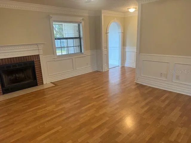 an empty room with wooden floor fireplace and windows