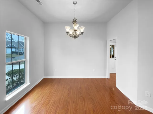 a view of a room with wooden floor chandelier and a window