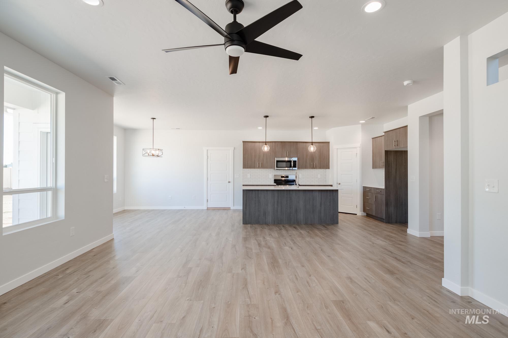 5304 Castleton Avenue Nampa, ID 83686 - Photo 13 of 25 Unfurnished living room with a ceiling fan, light wood finished floors, recessed lighting, and a chandelier