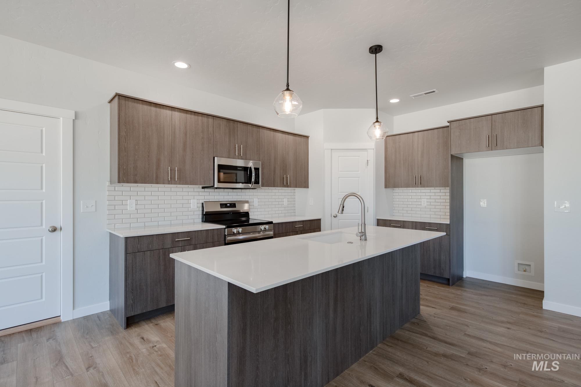 5304 Castleton Avenue Nampa, ID 83686 - Photo 4 of 25 Kitchen featuring decorative light fixtures, tasteful backsplash, stainless steel appliances, modern cabinets, and a kitchen island with sink
