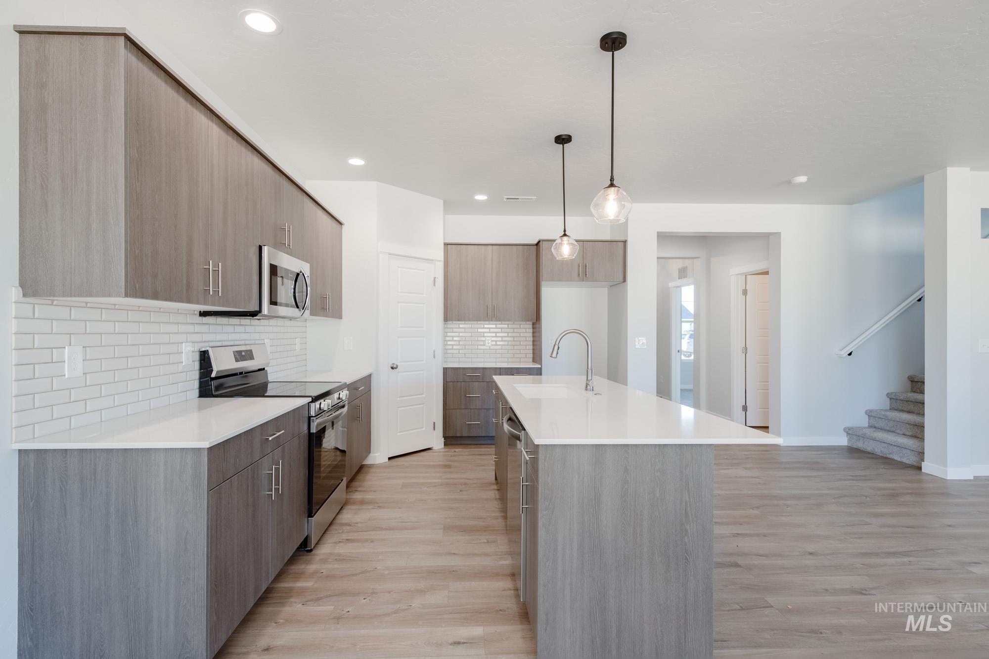 5304 Castleton Avenue Nampa, ID 83686 - Photo 8 of 25 Kitchen featuring stainless steel appliances, modern cabinets, decorative light fixtures, a center island with sink, and light stone counters