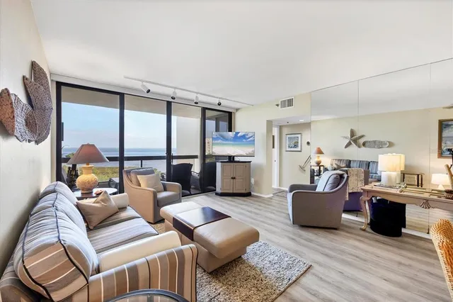 a living room with furniture kitchen view and a large window