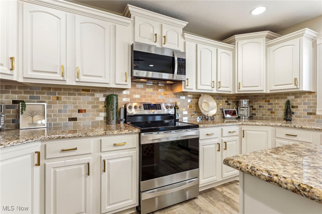 3353 Jens Way Perry, OH 44081 - Photo 19 of 49 Kitchen with white cabinetry, appliances with stainless steel finishes, light stone countertops, and light hardwood / wood-style floors