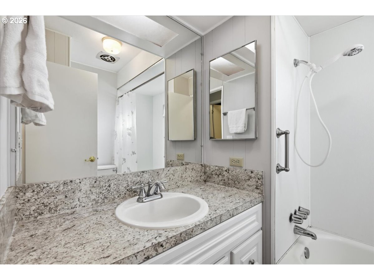 5422 Portland Road Northeast, Unit 33 Salem, OR 97305 - Photo 21 of 28 a bathroom with a granite countertop sink a mirror and shower