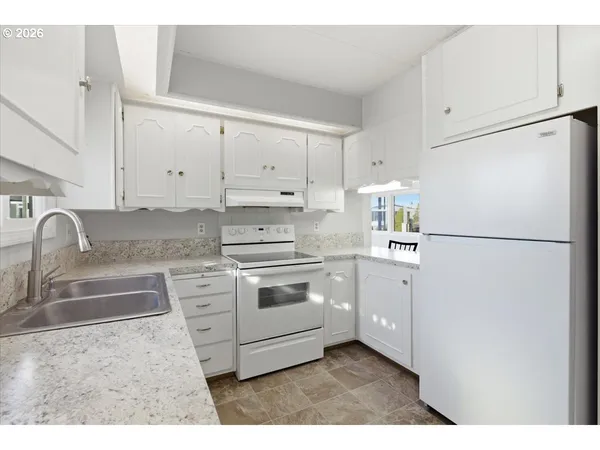 a kitchen with granite countertop white cabinets and white appliances
