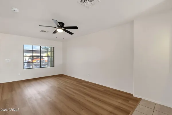 an empty room with wooden floor ceiling fan and windows