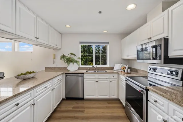 a kitchen with stainless steel appliances granite countertop white cabinets a sink and a stove