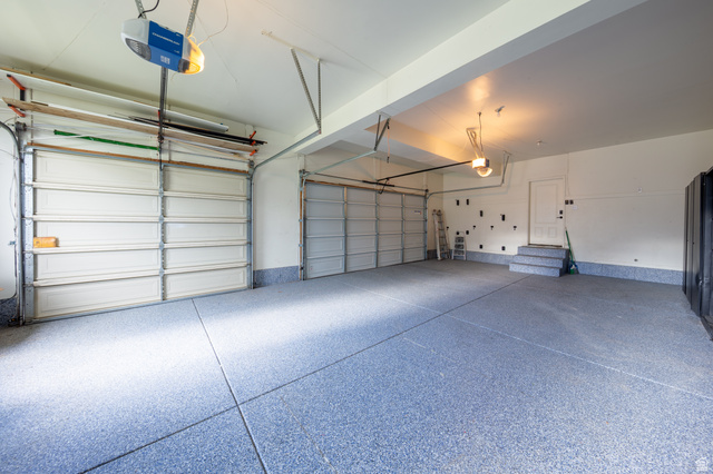 868 Braddock Lane Alpine, UT 84004 - Photo 54 of 64 Spacious garage featuring a durable speckled epoxy floor, two overhead garage doors, overhead garage door openers, and a utility door with a two-step entry